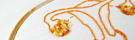 Uterus embroidered in orange and yellow thread on a white background