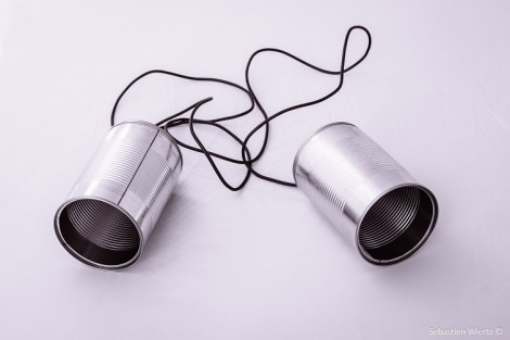 Two shiny silver cans attached by string for use as a childhood telephone
